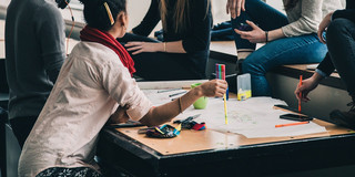 Studenten sitzen gemeinsam um einen Tisch und diskutieren
