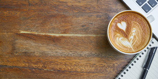Das Foto zeigt eine Kaffeetasse und einen Laptop.